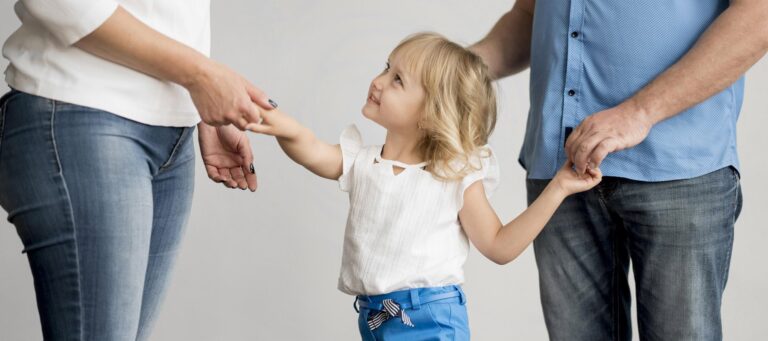 Niña de la mano con sus 2 padres. Custodia compartida