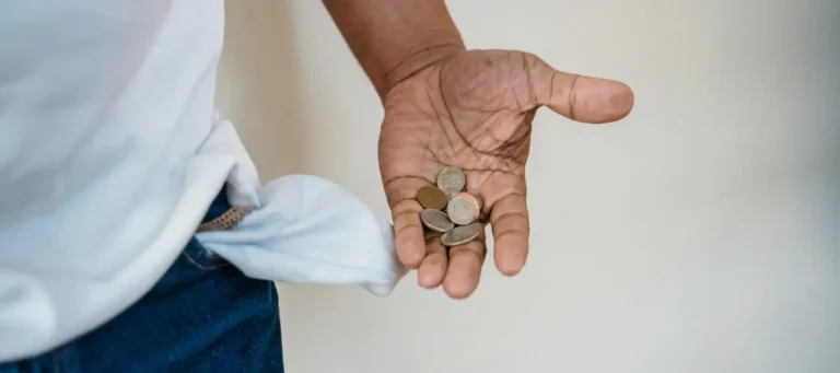 cliente hombre mirando las pocas monedas que tiene en la mano para pagar